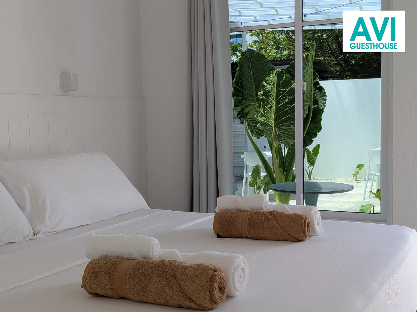 White double room with king-size bed, rolled towels and garden view